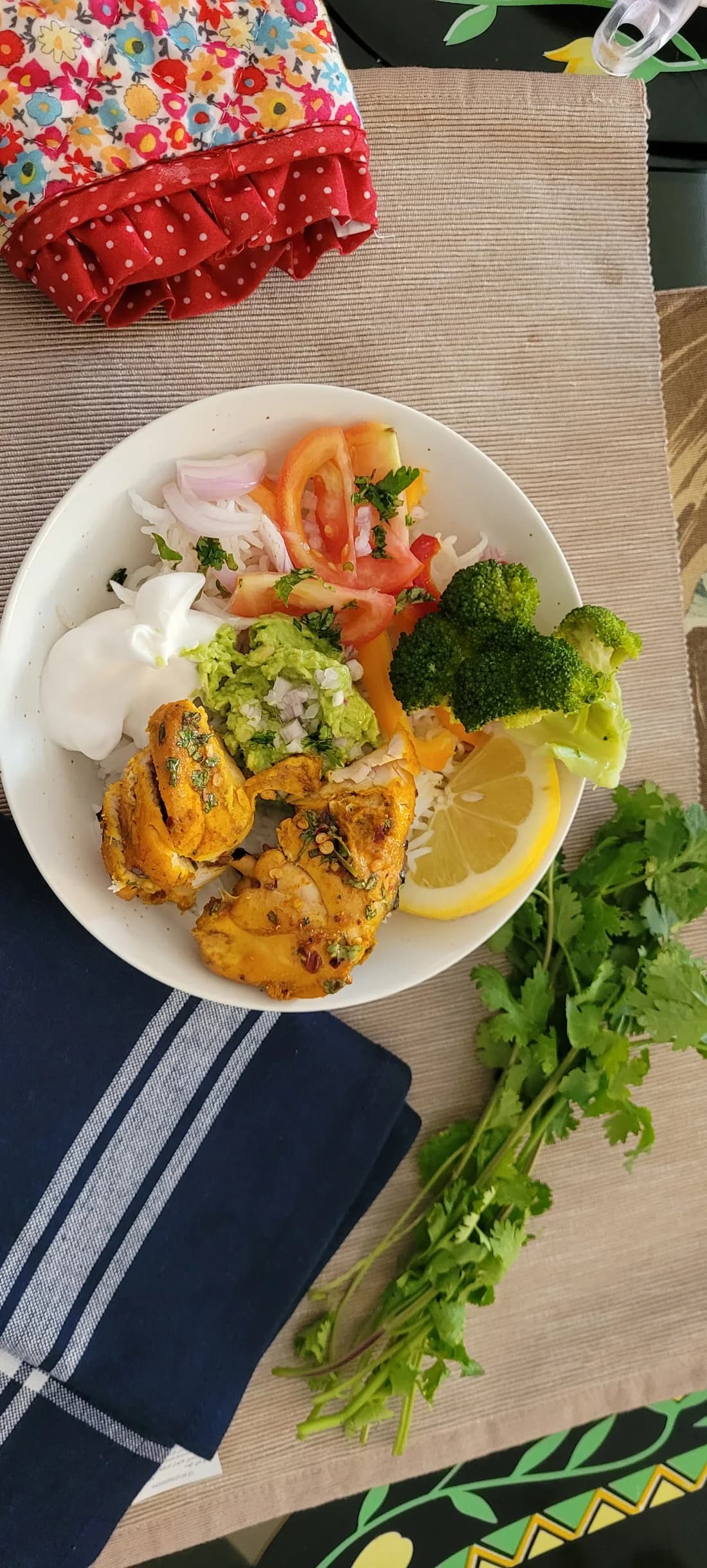 Finished chicken burrito bowl with chicken, rice, broccoli, avocado, yogurt, and lemon