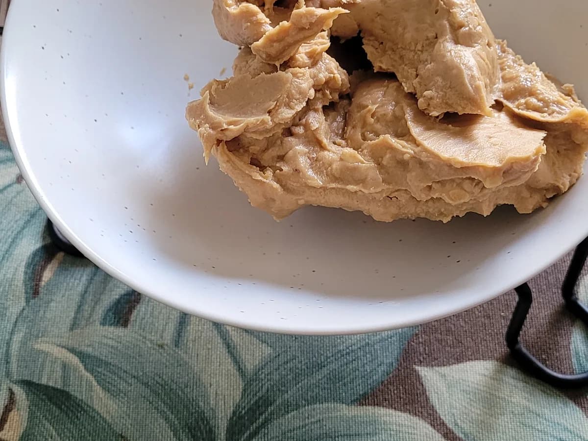 Creamy peanut butter added to a white mixing bowl